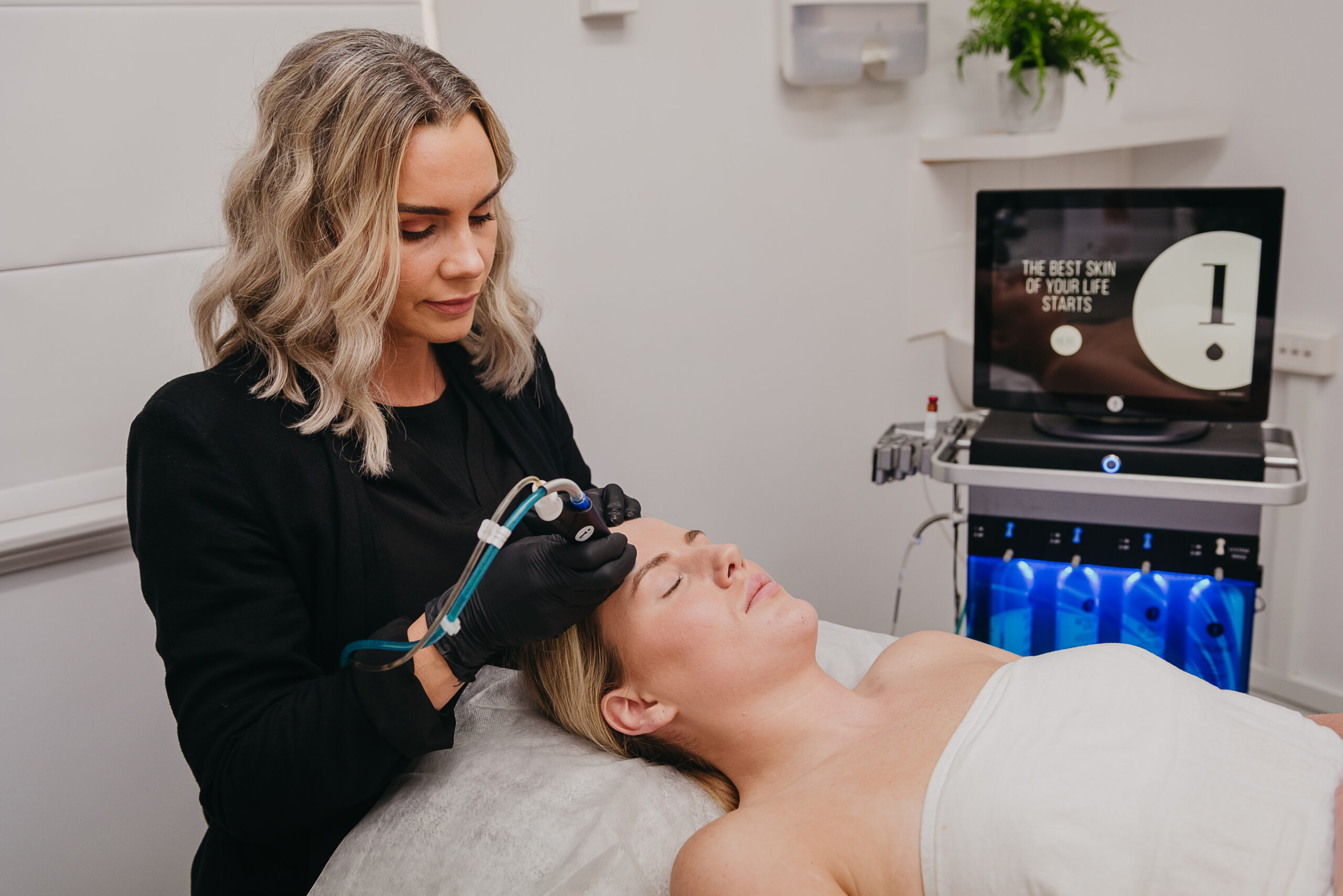 A woman laying down while receiving a Hydrafacial skin treatment.