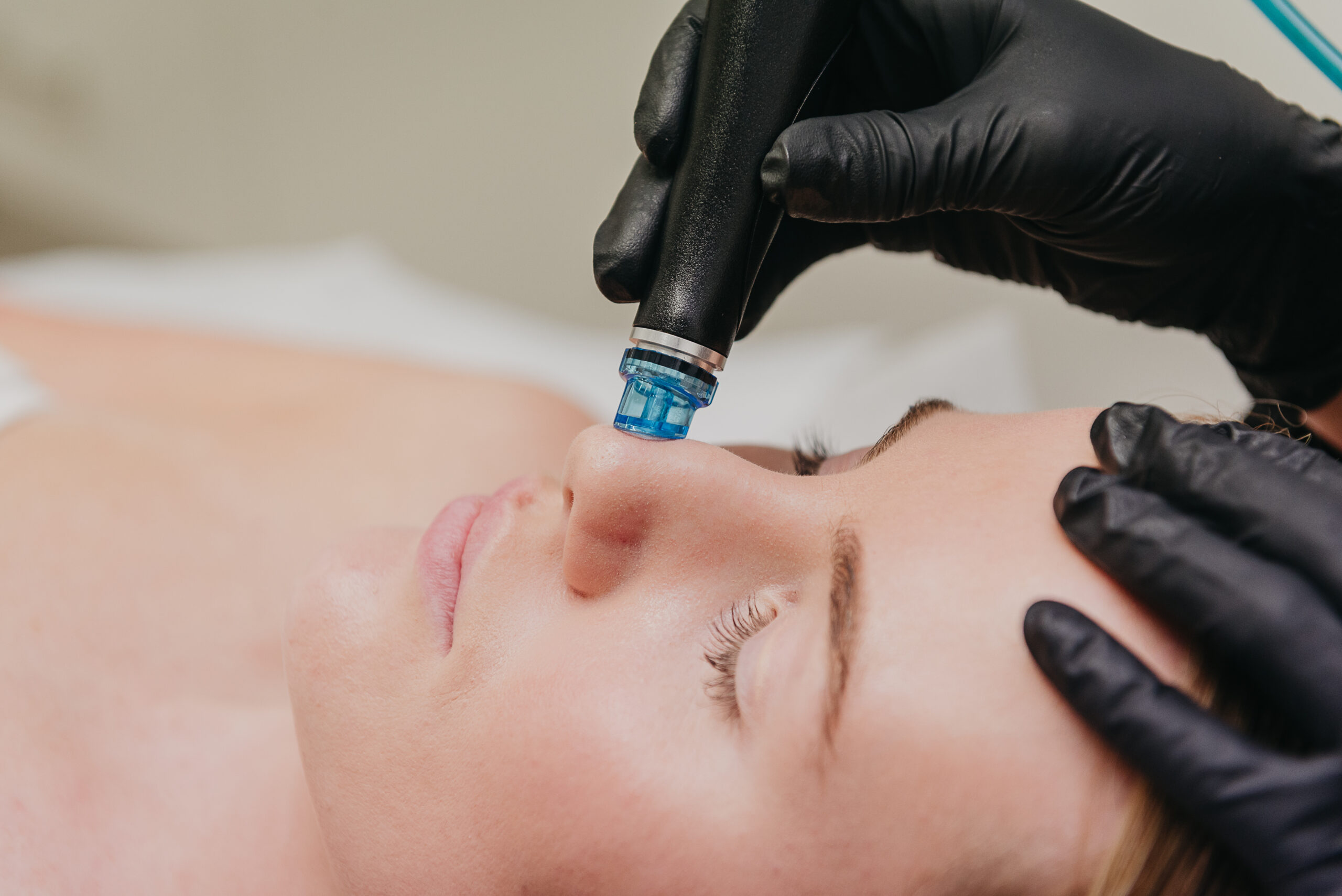 A woman laying down while receiving a Hydrafacial skin treatment.