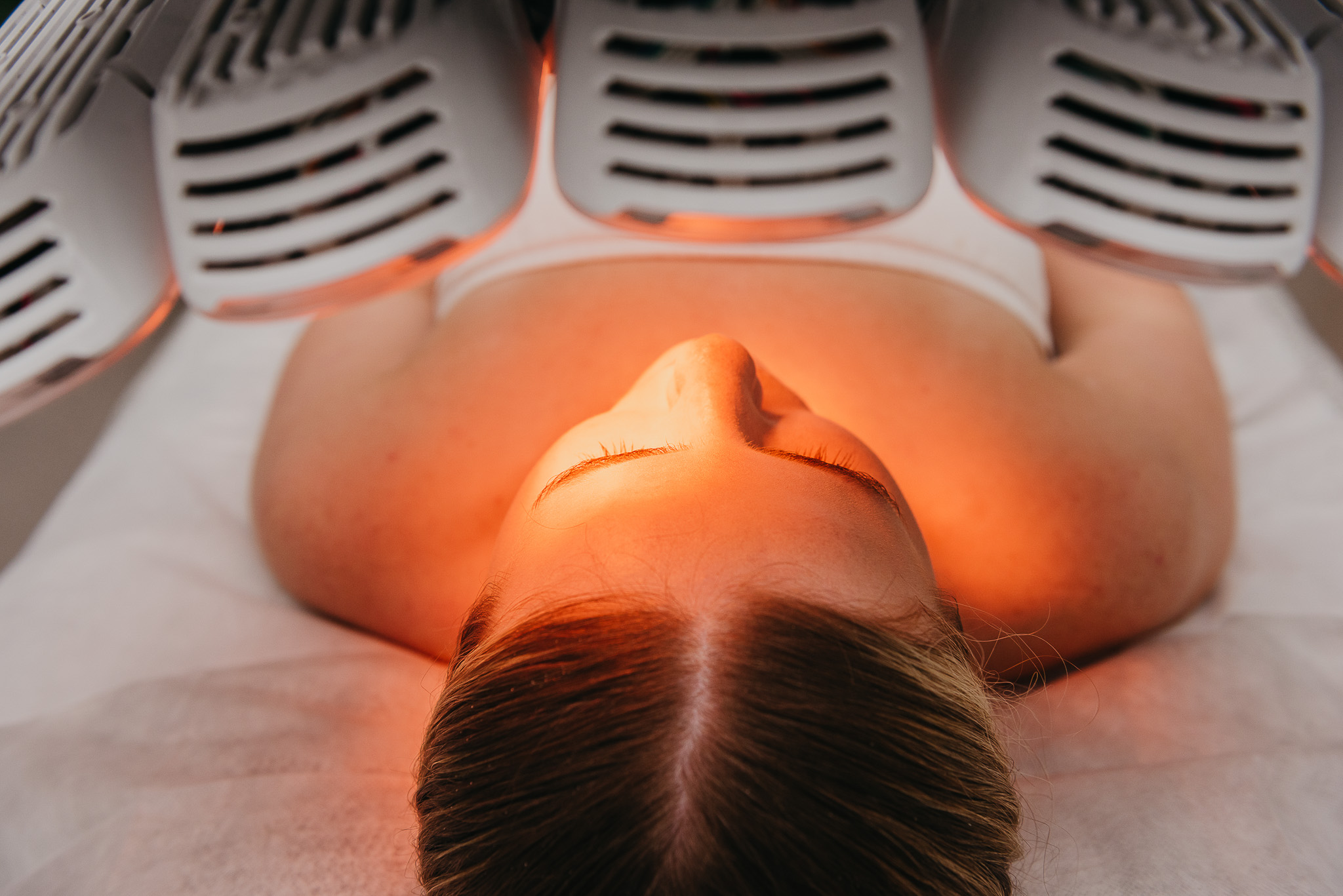 Woman laying down while receiving a UV skin care treatment.